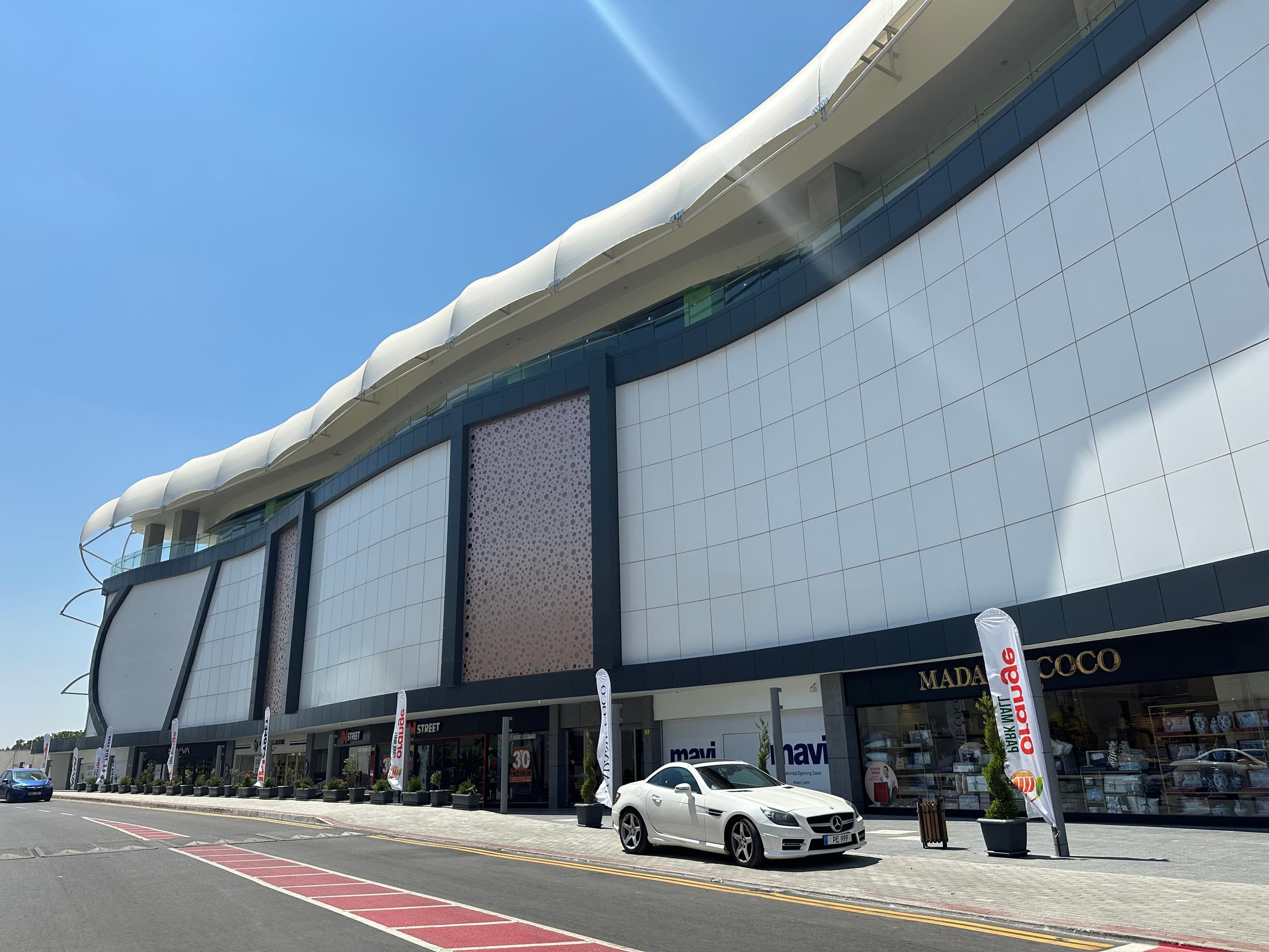 Güzelyurt Orange Mall: kavisli beyaz cephe ve gergi örtü saçak